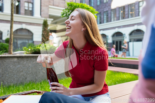 Image of Beautiful stylish young woman holding drink and relaxing in city street