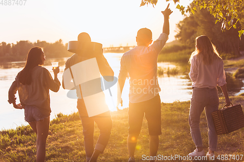 Image of Group of friends walking down during picnic at the beach. Lifestyle, friendship, having fun, weekend and resting concept.