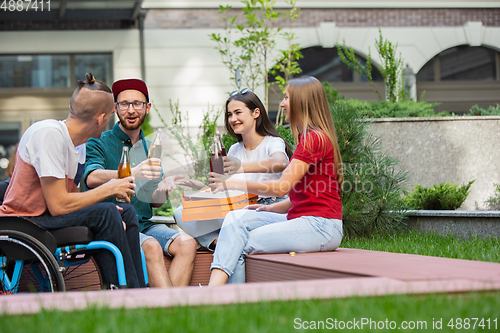 Image of Group of friends taking a stroll on city\'s street in summer day