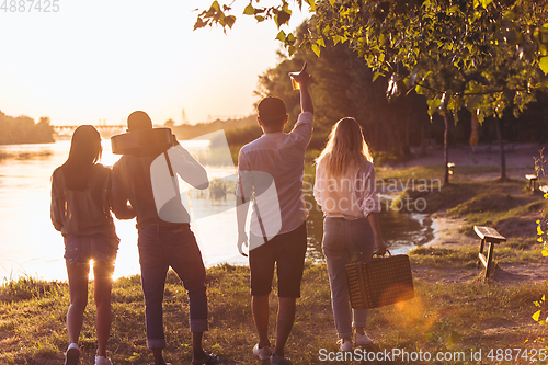 Image of Group of friends walking down during picnic at the beach. Lifestyle, friendship, having fun, weekend and resting concept.