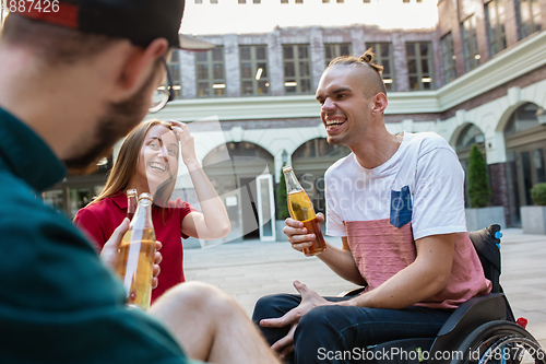 Image of Group of friends taking a stroll on city\'s street in summer day