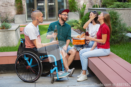 Image of Group of friends taking a stroll on city\'s street in summer day