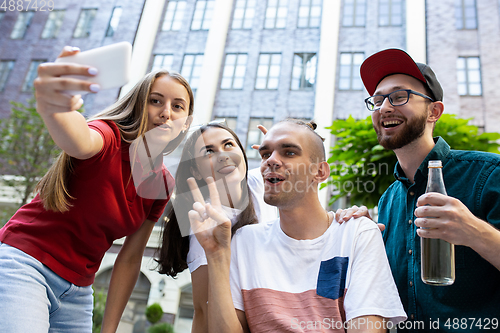 Image of Group of friends taking a stroll on city\'s street in summer day