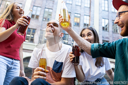 Image of Group of friends taking a stroll on city\'s street in summer day