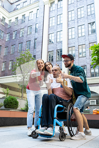 Image of Group of friends taking a stroll on city\'s street in summer day