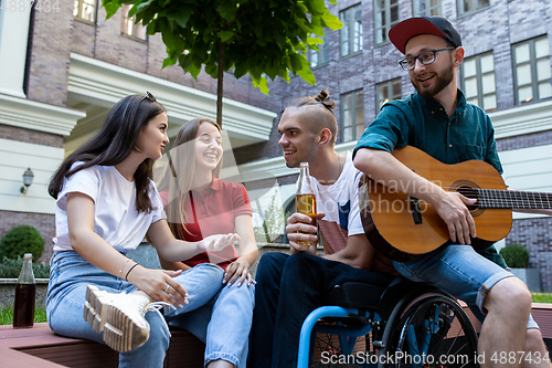 Image of Group of friends taking a stroll on city\'s street in summer day