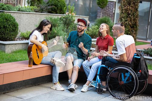 Image of Group of friends taking a stroll on city\'s street in summer day