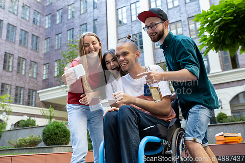 Image of Group of friends taking a stroll on city\'s street in summer day