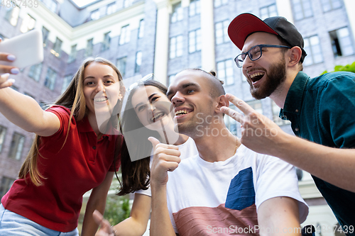 Image of Group of friends taking a stroll on city\'s street in summer day
