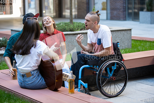 Image of Group of friends taking a stroll on city\'s street in summer day