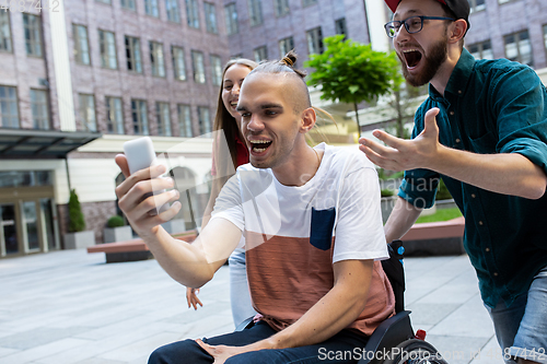 Image of Group of friends taking a stroll on city\'s street in summer day