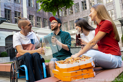 Image of Group of friends taking a stroll on city\'s street in summer day