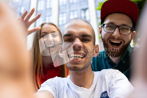 Image of Group of friends taking a stroll on city\'s street in summer day