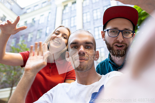 Image of Group of friends taking a stroll on city\'s street in summer day