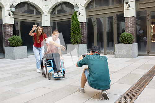 Image of Group of friends taking a stroll on city\'s street in summer day