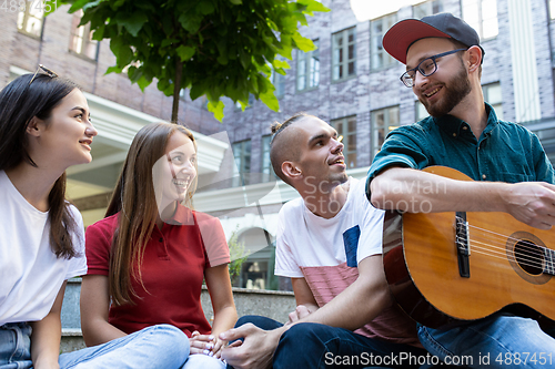 Image of Group of friends taking a stroll on city\'s street in summer day