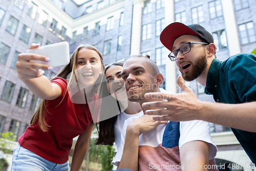 Image of Group of friends taking a stroll on city\'s street in summer day