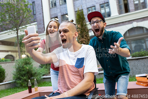 Image of Group of friends taking a stroll on city\'s street in summer day