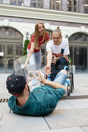 Image of Group of friends taking a stroll on city\'s street in summer day