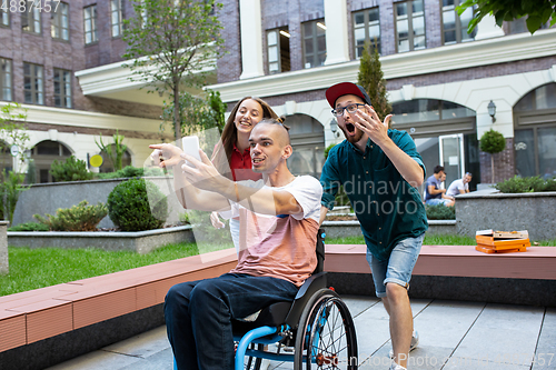 Image of Group of friends taking a stroll on city\'s street in summer day