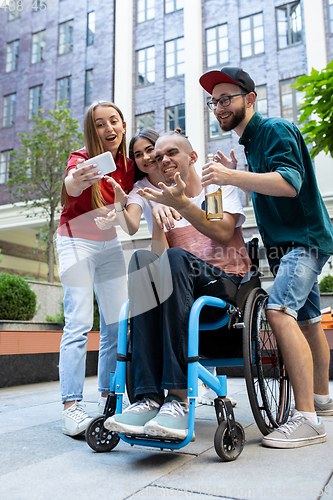 Image of Group of friends taking a stroll on city\'s street in summer day