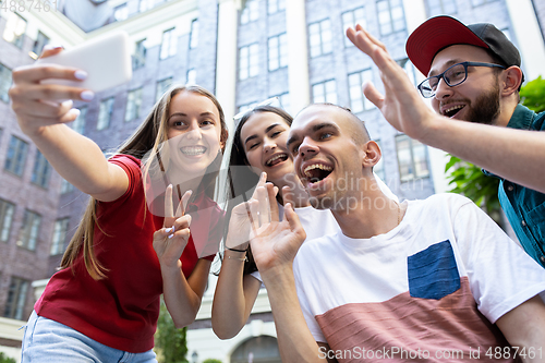 Image of Group of friends taking a stroll on city\'s street in summer day