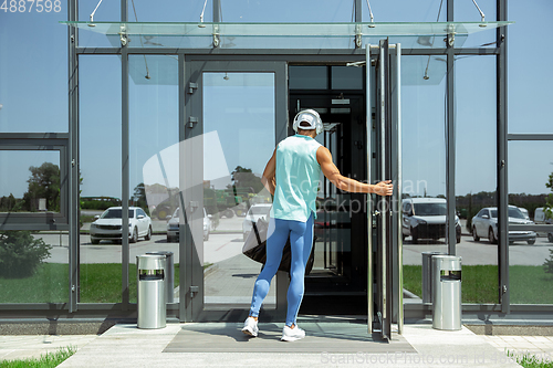 Image of Sports man against modern glassed building, airport in megapolis