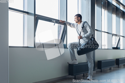 Image of Sports man against modern glassed building, airport in megapolis