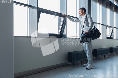 Image of Sports man against modern glassed building, airport in megapolis