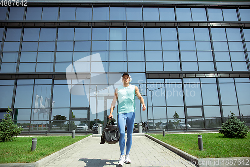 Image of Sports man against modern glassed building, airport in megapolis