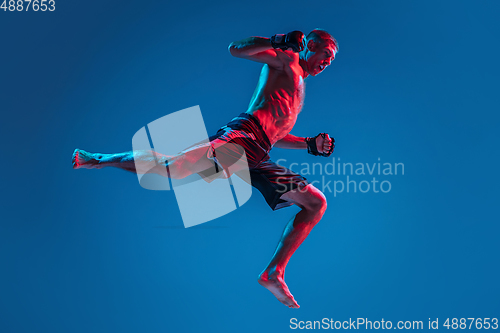 Image of MMA. Professional fighter punching or boxing isolated on blue studio background in neon