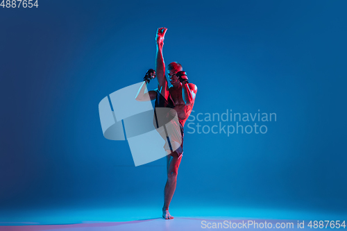 Image of MMA. Professional fighter punching or boxing isolated on blue studio background in neon