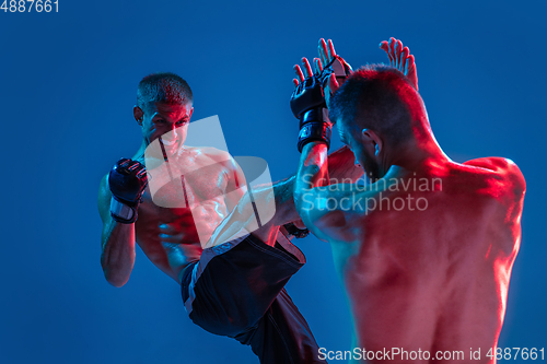 Image of MMA. Two professional fighters punching or boxing isolated on blue studio background in neon