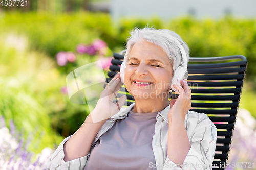 Image of happy senior woman with headphones at garden