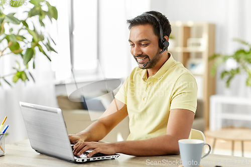 Image of indian man with headset and laptop working at home