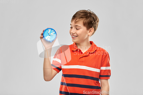 Image of portrait of happy smiling boy with alarm clock