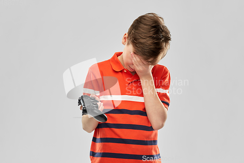 Image of unhappy boy with gamepad playing video game