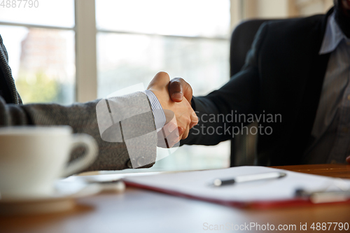 Image of Close up of businessmen shaking hands in conference room