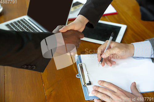 Image of Close up of businessmen shaking hands in conference room