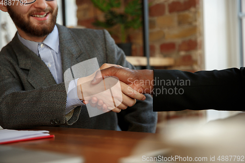 Image of Close up of businessmen shaking hands in conference room