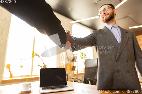 Image of Close up of businessmen shaking hands in conference room