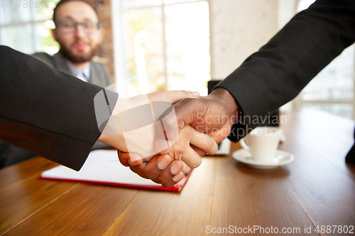 Image of Close up of businessmen shaking hands in conference room