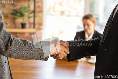 Image of Close up of businessmen shaking hands in conference room