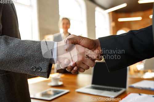 Image of Close up of businessmen shaking hands in conference room