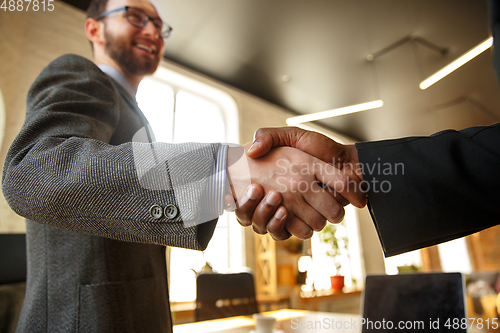 Image of Close up of businessmen shaking hands in conference room