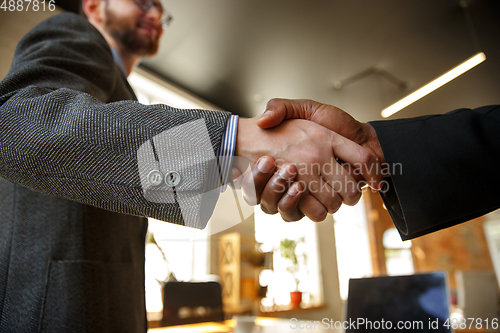 Image of Close up of businessmen shaking hands in conference room