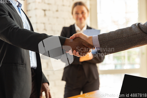 Image of Close up of businessmen shaking hands in conference room