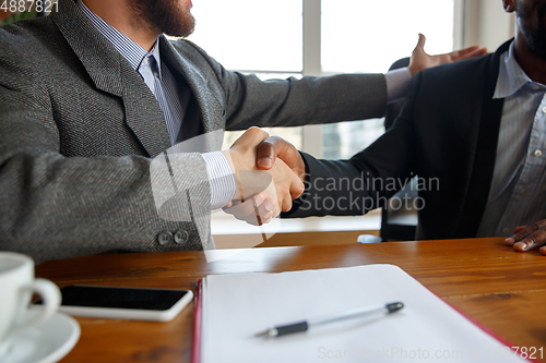 Image of Close up of businessmen shaking hands in conference room