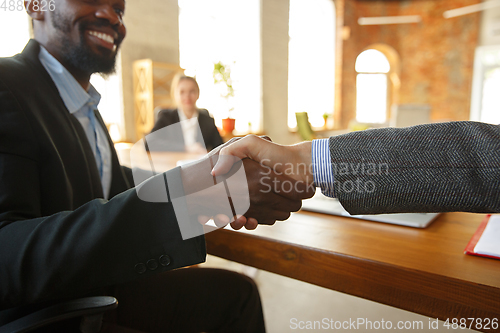 Image of Close up of businessmen shaking hands in conference room