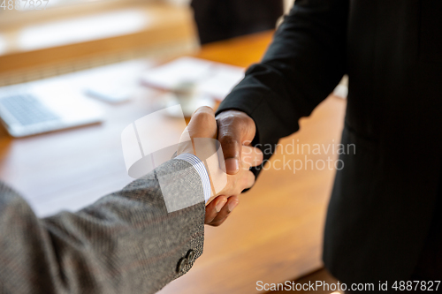 Image of Close up of businessmen shaking hands in conference room